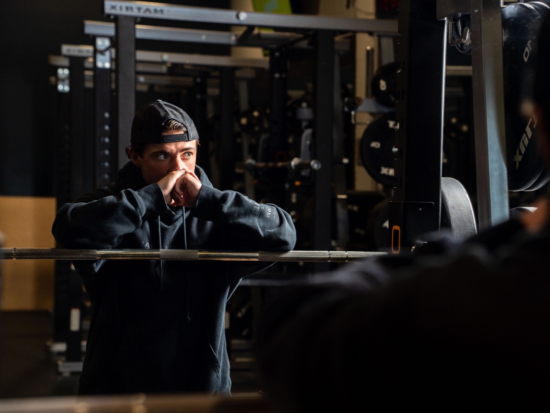 Athlete in a training hoodie at a squat rack